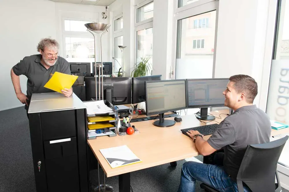 Foto eines senioren vitomed-Spezialisten und eines jungen IT-Fachmanns, die zusammenarbeiten